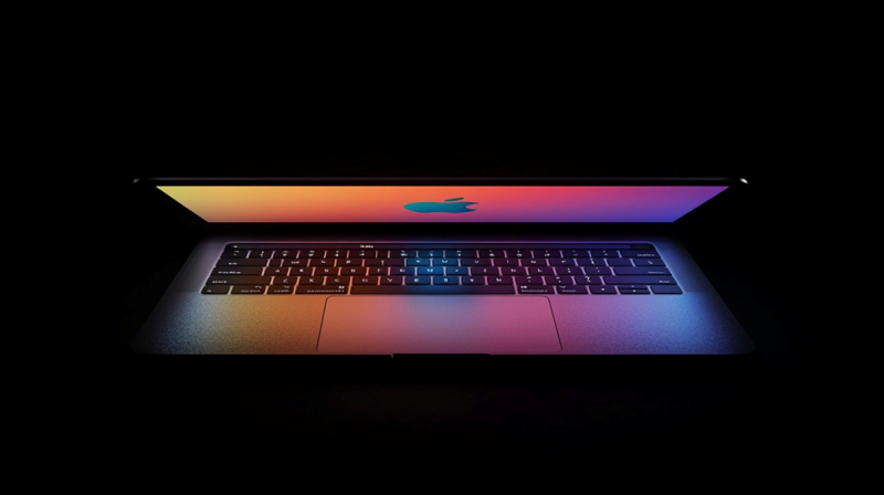 Полуоткрытый ноутбук MacBook с ярким экраном, освещающим клавиатуру, на темном фоне.